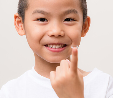 Child holding contact lens on finger