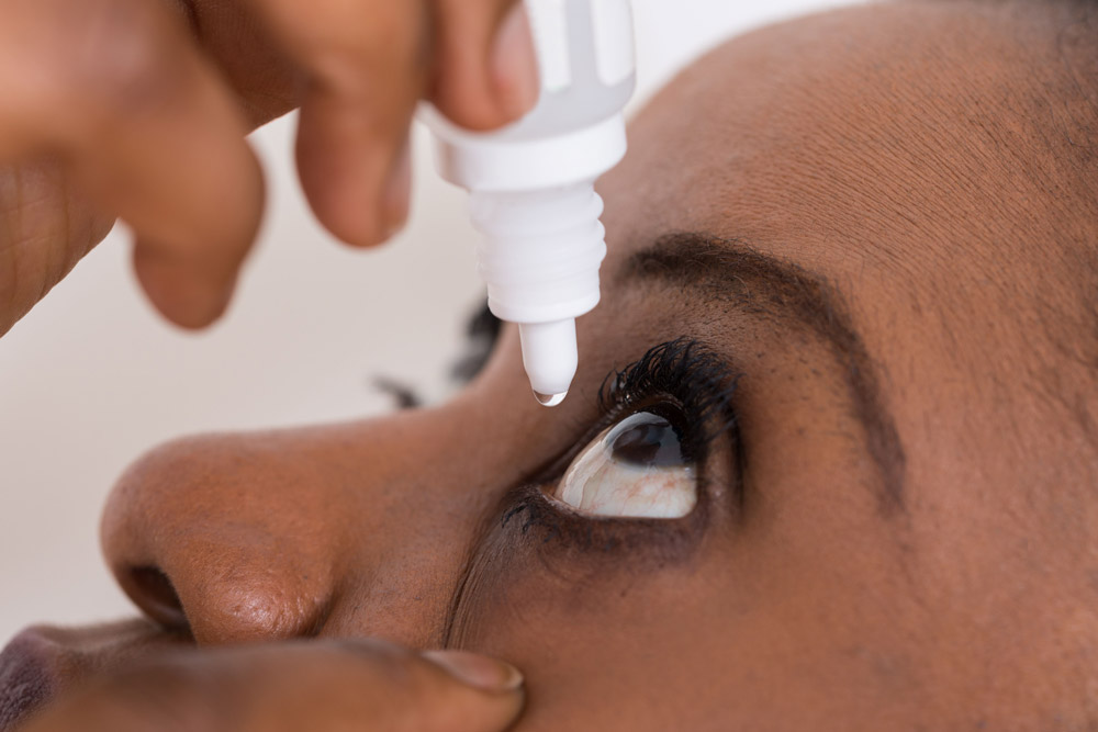 Woman administering eye drops for her eyes