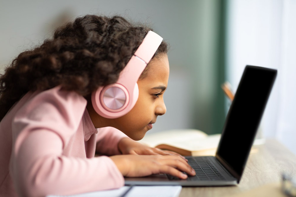 young girl having trouble reading laptop because of her myopia